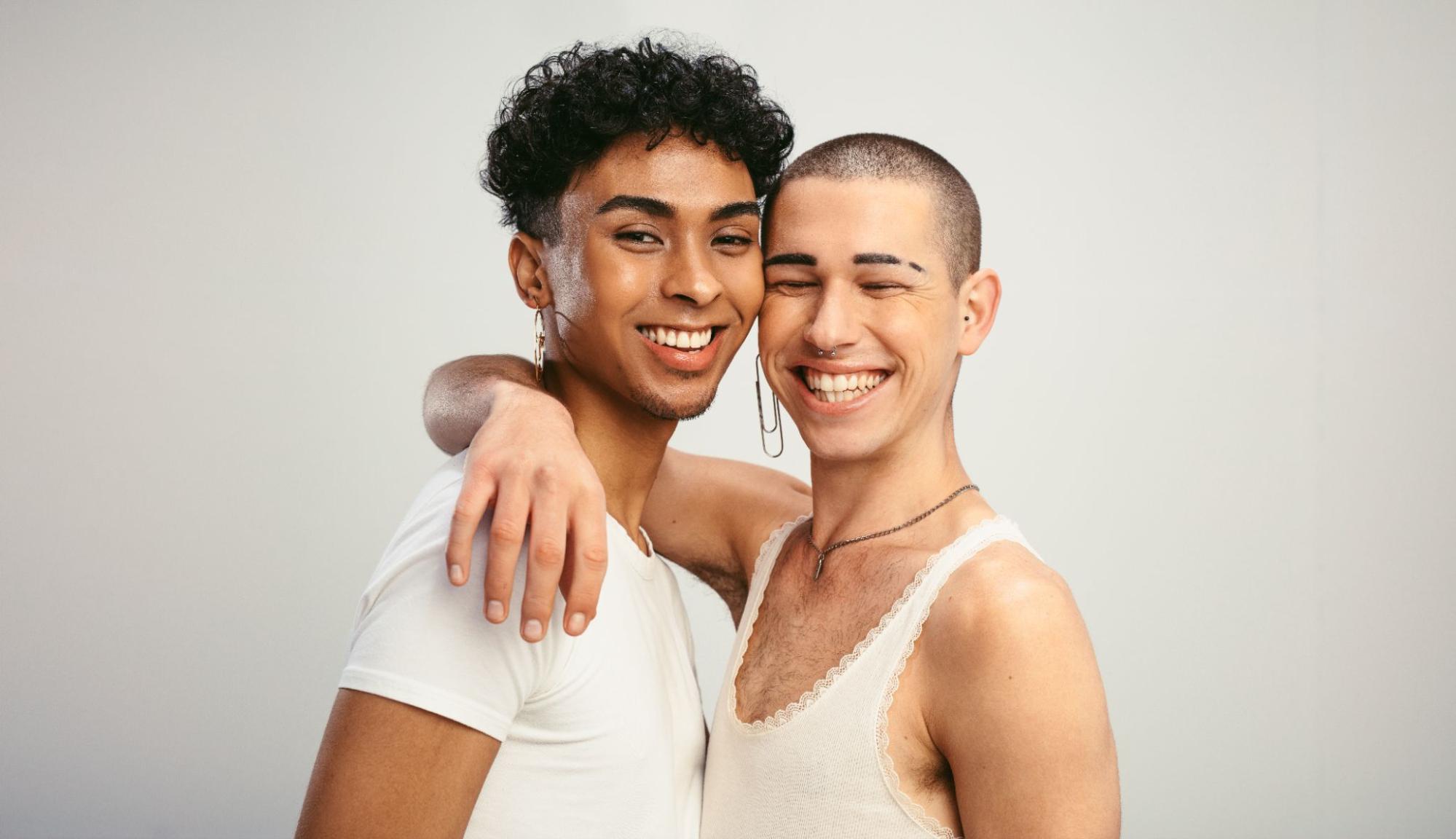 Two smiling friends standing together, expressing warmth and their gender identities