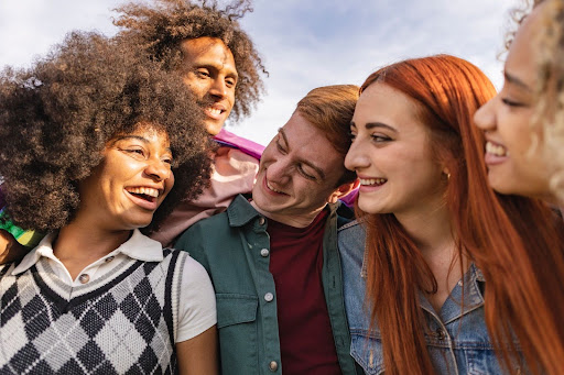 Diverse genders friend group of young people smiling and embracing
