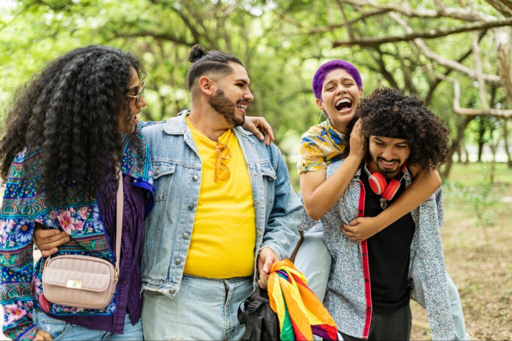 Group of diverse young adults laughing together outdoors, showing support and connection within LGBTQ+ community