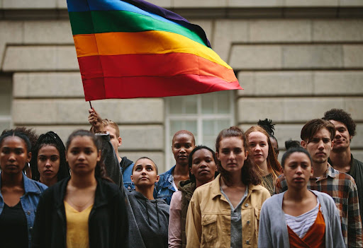 LGBTQ+ community members gathered in solemn with pride flag, raising awareness about LGBTQ+ domestic violence